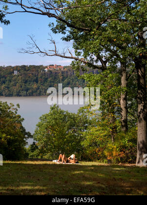 A summer sunbather relaxes in Fort Tryon Park, New York City. In background is the Hudson River and Englewood Cliffs, NJ. Stock Photo