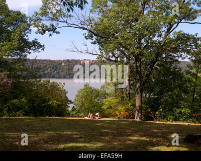 A summer sunbather relaxes in Fort Tryon Park, New York City. In background is the Hudson River and Englewood Cliffs, NJ. Stock Photo