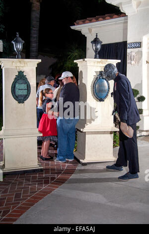 A costumed gravedigger in a fright mask with a shovel is the host at the entrance of a Halloween night 'haunted mansion' in Lake Forest, CA. Note visitors. Stock Photo