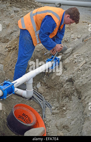A plumber tightens the joiners on pipes for a new stormwater drainage system Stock Photo