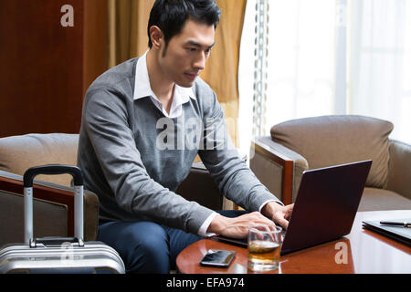 Young businessman using laptop in hotel room Stock Photo