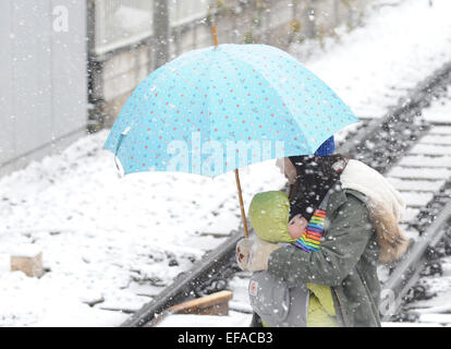 Tokyo, Japan. 30th Jan, 2015. A woman holding a baby in her arm walks across a railroad track amid snow in Tokyo, Japan, Jan. 30, 2015. Credit:  Stringer/Xinhua/Alamy Live News Stock Photo