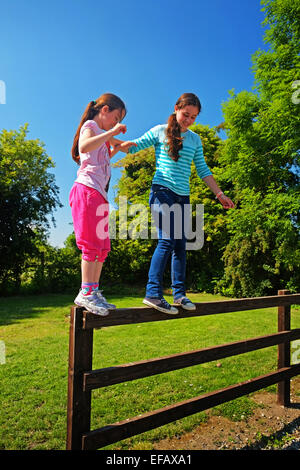 Two young sisters tight rope walking on a fence in North County Dublin Ireland Stock Photo