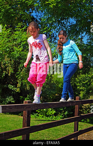 Two young sisters tight rope walking on a fence in North County Dublin Ireland Stock Photo