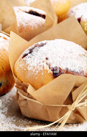 Muffins with jam sprinkled with powdered sugar on wooden tray Stock Photo