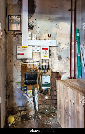 Poorly maintained and dangerous outdated electrical wiring and fuseboxes, mounted on a damp wall in an old building Stock Photo