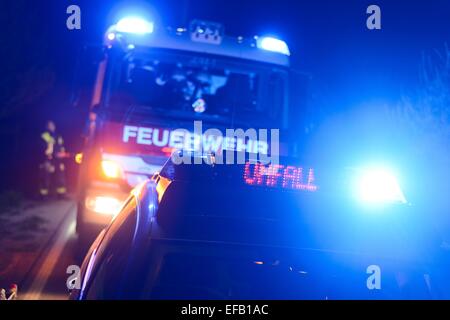 Fire engine and police car with flashing blue lights and the LED display 'Unfall', German for 'accident', at a crash site Stock Photo