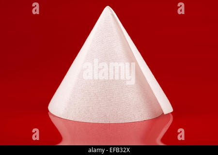 Disposable  kitchen paper shaped into a cone on a red background from Ora Stock Photo