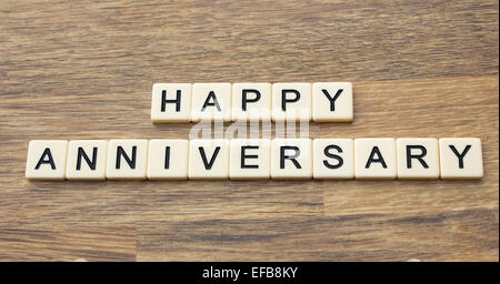 The word happy anniversary written in tiles on a wooden surface Stock Photo