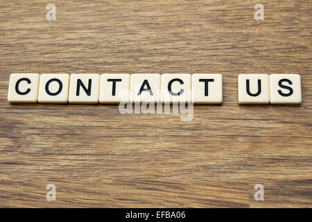 The word contact us written in tiles on a wooden surface Stock Photo