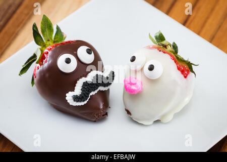 two strawberries on a white plate dipped in chocolate and decorated for a romantic concept Stock Photo