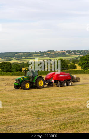 Tractor and hay baling baling hay in field, Oxfordshire, England Stock Photo