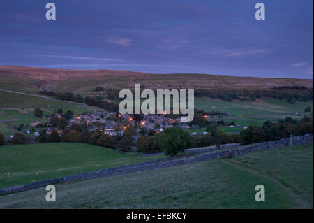 Kettlewell village, nestling in scenic valley below upland moors & hills, street lights lit at nightfall - Wharfedale, Yorkshire Dales, England, UK. Stock Photo