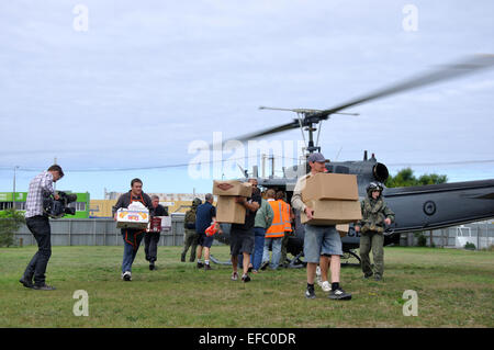 CHRISTCHURCH, NEW ZEALAND, February 22, 2011: Volunteer relief workers scramble for food supplies from an Air Force helicopter Stock Photo