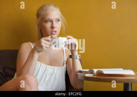 Young blonde woman drinking coffee at cafe Stock Photo