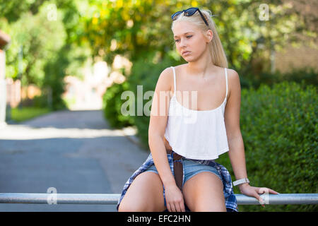 Thoughtful and sad young girl sitting outdoor Stock Photo