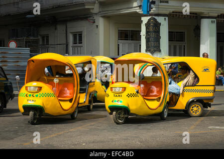 Cuba Old Havana La Habana Vieja bright yellow scooter three wheeler Coco cabs taxis rickshaws rank Central Park Stock Photo