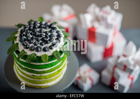 Nice sponge happy birthday cake with mascarpone and grapes with on the cake stand with gift boxes on festive light bokeh backgro Stock Photo