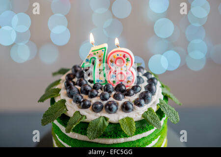 Nice sponge happy birthday cake with mascarpone and grapes on the cake stand with candles on festive light bokeh Stock Photo