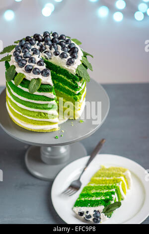 Cuted piece of green sponge cake on the plate on festive background with bokeh light