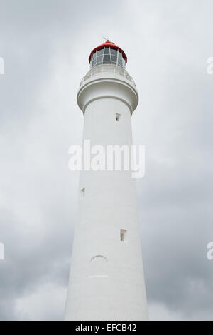 A light house with a red roof in front of stormy clouds. Stock Photo