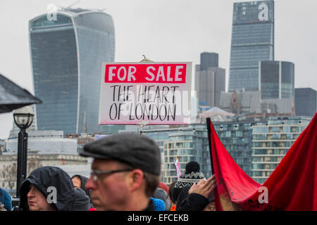 London, UK. 31st Jan, 2015. A rally at the end at the foot of City Hall and sandwiched between the City and a new development of luxury flats at One Tower Bridge. People marched from South London and East London to City Hall to demand better homes for Londoners and an end to the housing crisis. Demands included rent controls, affordable and secure homes for all, an end to the Bedroom Tax and welfare caps and the building of new council houses. The event was called by Defend Council Housing and  South London People's Assembly. And the East London route started at Parish Church of St. Leonard, S Stock Photo