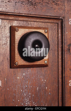 Vintage bakelite black electric light switch mounted on wood and screwed to wooden panel with signs of wear Stock Photo