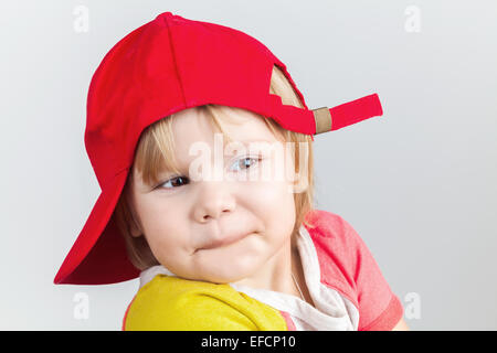 Baby in a baseball cap smiling out of 
