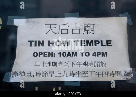 Sign at the Tin How Temple on Waverly Place in Chinatown telling visitors of the open hours in English and Chinese. Stock Photo