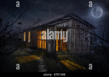 Rural house with glowing windows at night sky with moon Stock Photo