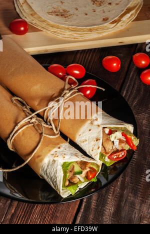 Mexican tortilla wrap with meat and vegetables on wood table Stock Photo