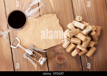 Wine glasses, corks, corkscrew and piece of paper for copy space over rustic wooden table background. Top view Stock Photo