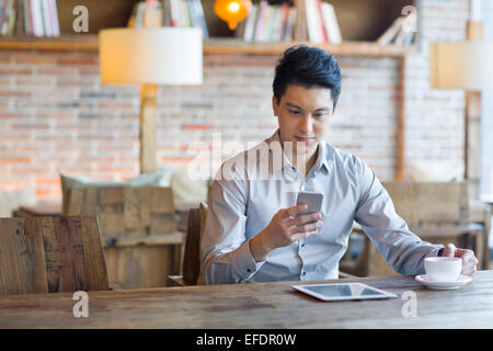 Young man using smart phone in cafe Stock Photo