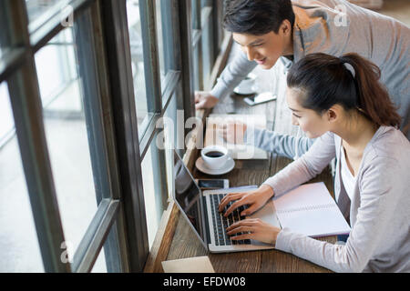 Young man and woman using laptop in cafe Stock Photo