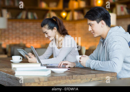Young man and woman using laptop and digital tablet in cafe Stock Photo