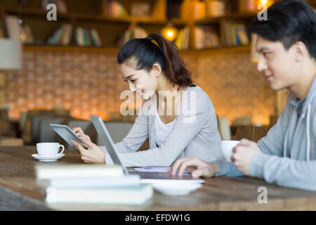 Young man and woman using laptop and digital tablet in cafe Stock Photo
