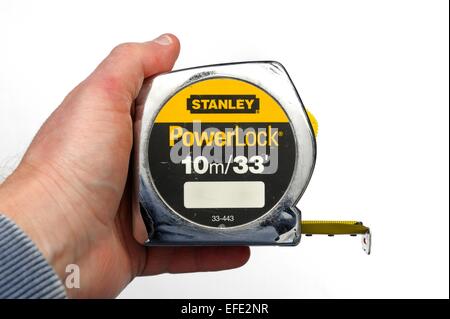 A Chrome tape measure being held in a man's hand Stock Photo