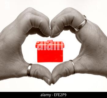 Female hands in a heart shape with a red house digitally added Stock Photo