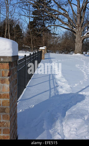 Iron and brick fence on a peaceful sunny snow covered winter day in the park Stock Photo