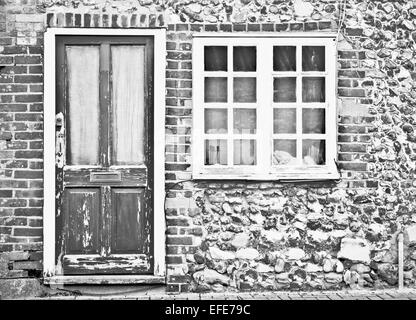 Front of an old cottage with peeling paint on the door and wondow Stock Photo