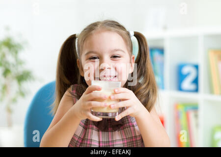 little girl drinking milk from glass indoor Stock Photo