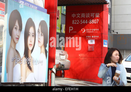 (150202) -- SEOUL, Feb. 2, 2015 (Xinhua) -- A woman walks past a plastic surgery advertisement on the famous plastic surgery street near Apgujeon, Seoul, South Korea, on Feb.2, 2015. With over 200 plastic surgery clinics gathered here, Apgujeon is best known as the center of South Korea's plastic surgery industry according to the local media. In recent years, many Chinese tourists flood to Seoul for plastic surgery. As many problem remains in the fast-growing market for medical tourism, the number of medical disputes also increased. The brain death of a 50-year-old Chinese woman following a su Stock Photo