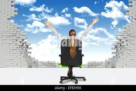 Businesswoman sitting on the office chair in front of broken wall Stock Photo