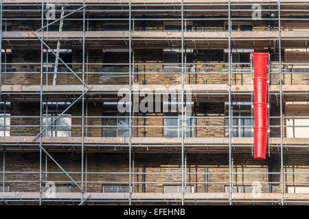 Red waste chute on scaffold frame Stock Photo
