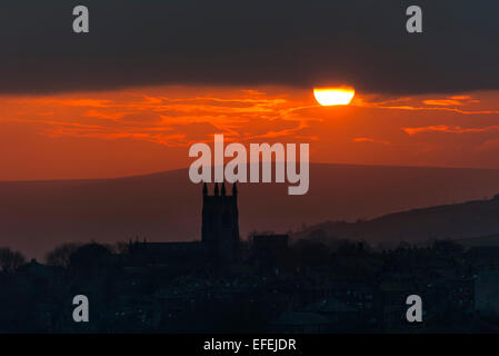 A warm winter sun sets over the hills of the South Pennines silhouetting the Church in the Yorkshire village of Heptonstall near Stock Photo