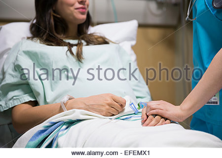 Nurse holding hands with pregnant woman in hospital
