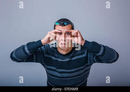 European-looking male of about thirty brunet stretches eyes with Stock Photo