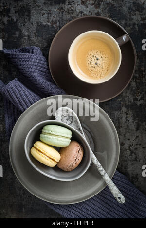 Colourful macarons in a small cup with y cup of coffee Stock Photo