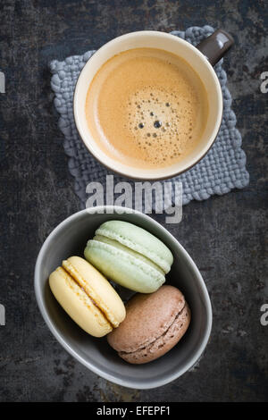 Colourful macarons in a small cup with y cup of coffee Stock Photo