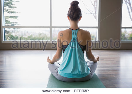 Rear view of woman meditating in lotus position